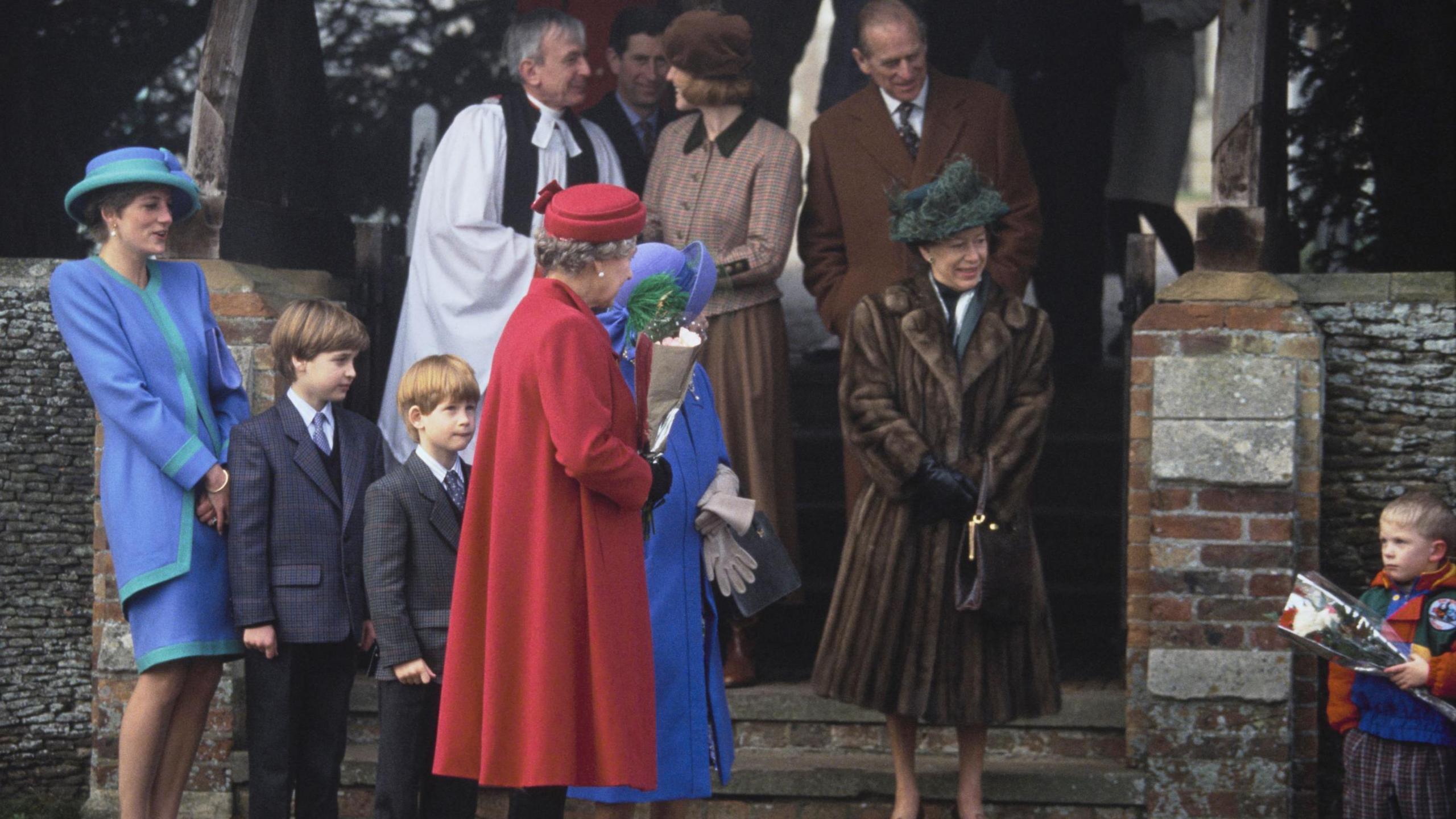 Christmas Day 1991 and the Royal family leaves St Mary Magdalene Church on the Sandringham Estate. The late Princess Diana (far left) is laughing and Queen Elizabeth, the Queen Mother and Princess Margaret are on the front of the church with young Princes William and Harry. A young boy awaits holding flowers. Prince Philip is behind them all with King Charles in the far background. A vicar wearing black and white can be seen too. 