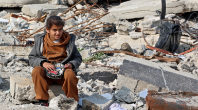 A Palestinian girl sits amid the rubble of buildings destroyed in Israeli airstrikes, in Gaza City