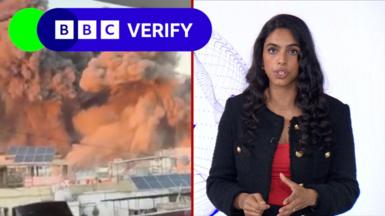 BBC reporter Merlyn Thomas in front of footage of bombed buildings