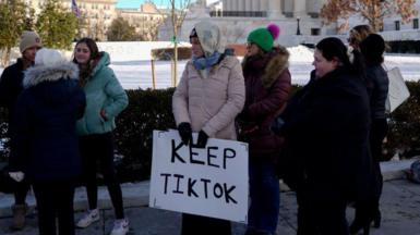 A group of young people holding a sign reading 'Keep TikTok' stand in cold-weather clothes outside the Supreme Court in the US.