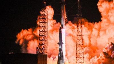 Smoke and flames in the background as a rocket prepares to launch into orbit