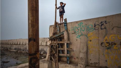 A boy walks on the newly built sea wall that protects Jakarta from the rising sea levels