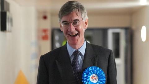 Jacob, smiling, wearing a blue conservative rosette and a black jacket