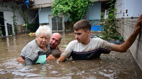 Local residents rescue an elderly person from the rising flood waters in the Romanian village of Slobozia Conachi