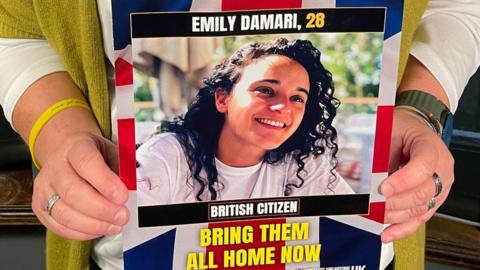 Mandy Damari holds up a photo of her daughter Emily Damari, who is being held hostage by Hamas in the Gaza Strip, during a visit to the UK (3 December 2024)