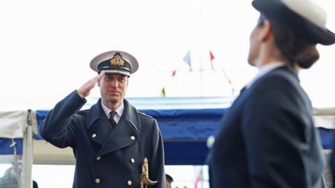 The prince salutes as the new officers pass him