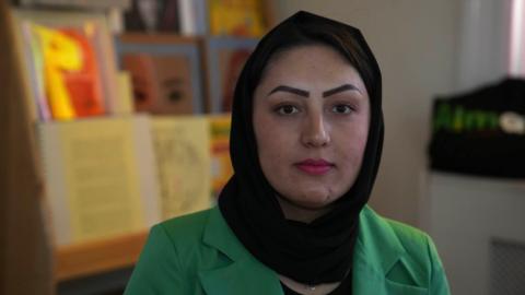 Feriba Almas wearing a black hijab and a green blazer. She is looking into the camera and not smiling 