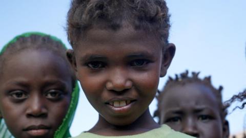 Three children in Sudan stare directly at the camera