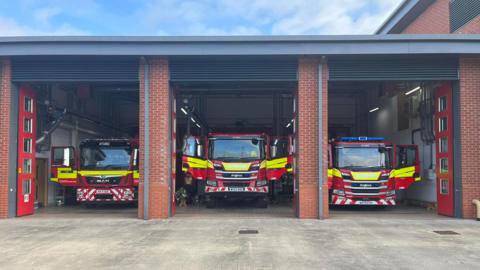 The front of Poole fire station with three sets of doors open, each with a fire engine with their doors open.