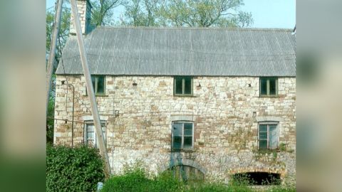 Old Mill building made of old stone with three windows on first floor and three smaller windows on second floor