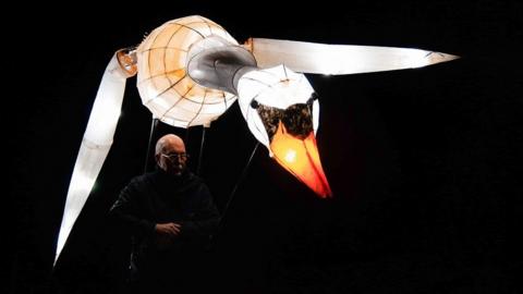 A man controls a model of a swan