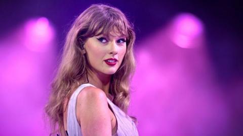 Taylor Swift on stage at Wembley with a purple background