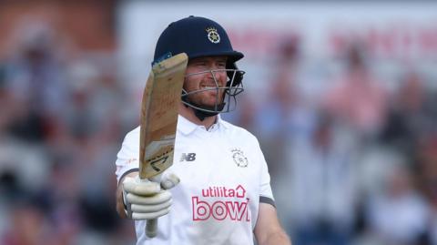 Liam Dawson raises his bat at Old Trafford to acknowledge his hundred