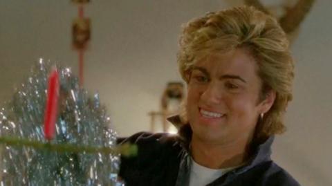 George Michael hangs tinsel and other Christmas decorations in an outtake from the video for Last Christmas.