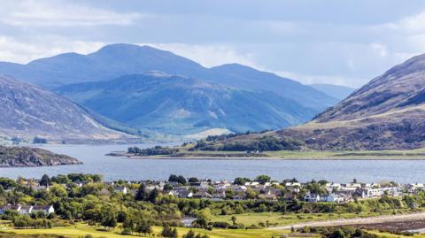 The village of Ullapool on the shores of Loch Broom with mountains and hills in the background.