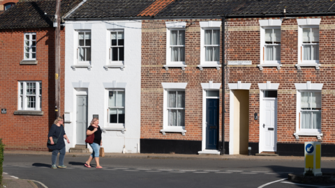 A stock image of a row of houses with a variety of brickwork and white framed windows