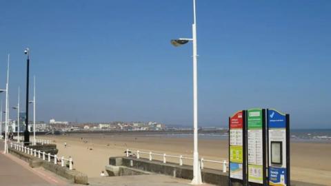 View of the beach at Bridlington from the promenade with the sea and buildings in the background.