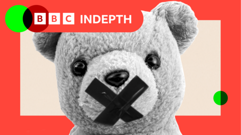 A stylised black-and-white image of a teddy bear with a bold black X over its mouth. Only the upper half of the bear is visible, set against a light peach background. The image is framed by a vibrant red border, with two small green circles added for contrast—one in the top left corner and the other in the bottom right corner.