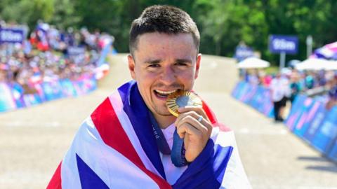 Tom Pidcock bites his Olympic gold medal