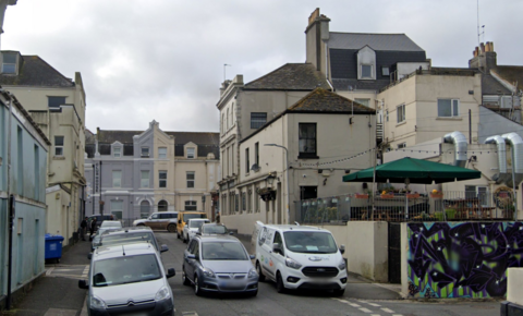 Google Maps image of Moor View Terrace. Cream buildings are built on either side of the narrow side street. A number of cars and vans are parked on either side of the road. 