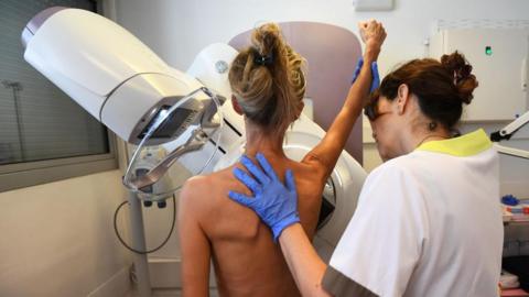 Female health care worker assisting woman getting a mammogram 