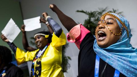 Two female activists dressed in traditional costumes perform an action to celebrate the children at the COP29 United Nations climate change conference, in Baku