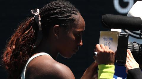 Coco Gauff signs the camera lens with 'Stay strong LA, thank you firefighters'