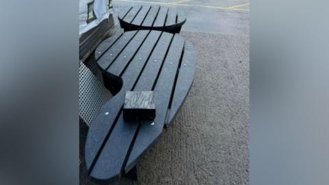 A black bench that is shaped like a semi-colon