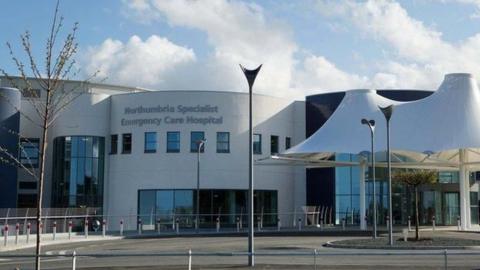 The Northumbria Specialist Emergency Care Hospital. The building has a glass-fronted entrance while the rest is made of white panelling.