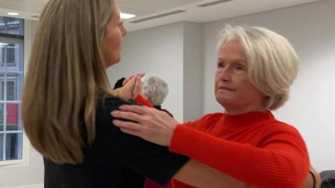 A dancing instructor teaching a blind woman ballroom dancing