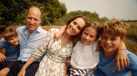 Prince and Princess of Wales and their three children in a photo in front of trees and greenery in Norfolk, taken in August and used for their Christmas card.