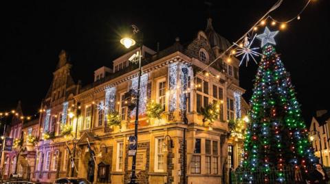 Douglas City Hall, illuminated with  whiteChristmas lights, with a large Christmas tree next to it. 