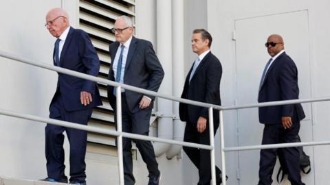 Rupert Murdoch and others walk outside a Reno courthouse