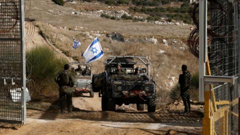 Israeli military vehicles cross the fence as they return from the buffer zone with Syria, near the Druze village of Majdal Shams in the occupied Golan Heights on December 10, 2024