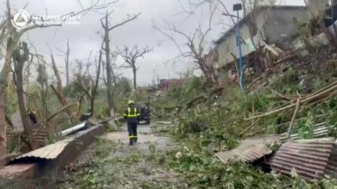 Rescuer amongst debris and fallen trees in the street