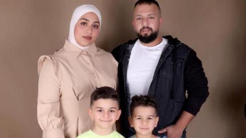 Mahasen al-Dada poses for a photograph in a beige coat, with her arm around her husband. Their two boys stand in front of them.