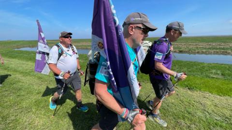 Three men walking along Norfolk coastal path