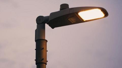 A streetlight that is on. 