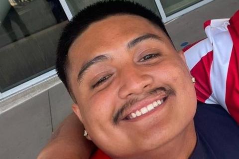 Close up selfie of smiling young man with short black hair and a thin moustash, wearing diamond stud earrings.