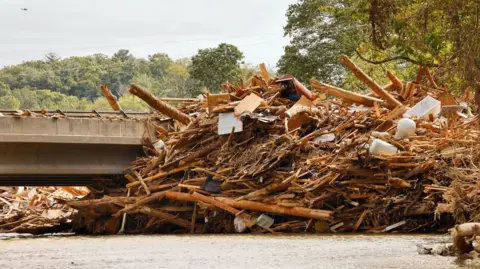 A mass of debris - mostly wood - stretches around a bridge in Chimney Rock, North Carolina