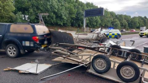 A trailer with fridges and worktops is seen spilled out on the M5 motorway, behind a 4x4 and two police cars.