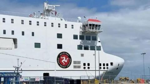 The bow of the Manxman, a box like white ferry, with the three legs of man along with the Isle of Man Steam Packet Company written on the side of the boat.