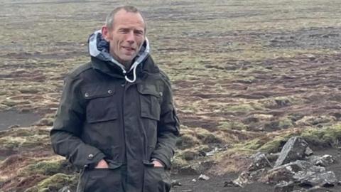 Richard Locker standing on moorland. He's wearing a dark coat and has light hair