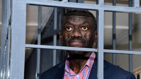 Kizza Besigye looks through a metal grille at the Uganda Military General Court Martial that sits in Makindye suburb of Kampala, Uganda November 20, 2024