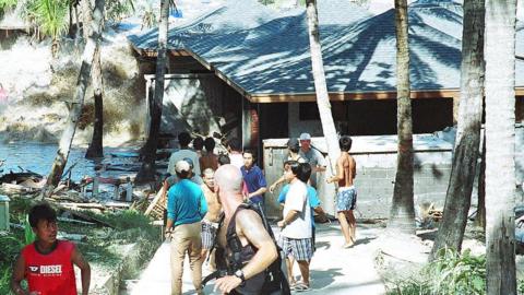 This photo taken 26 December 2004 shows people fleeing as a tsunami wave comes crashing ashore at Koh Raya, part of Thailand's territory in the Andaman islands and only some 23 kilometers from Phuket island, southern Thailand. Over one week after tidal waves ripped into southwestern tourist resorts and fishing areas, the country's confirmed death toll was just over 5,000, including nearly 2,500 foreign holidaymakers, with 3,810 people missing. 