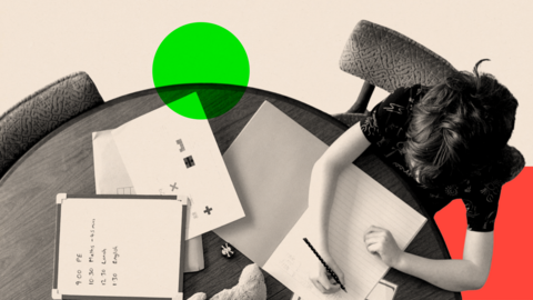 Children sit around a circular table with textbooks, paper, a clock and a teddy bear