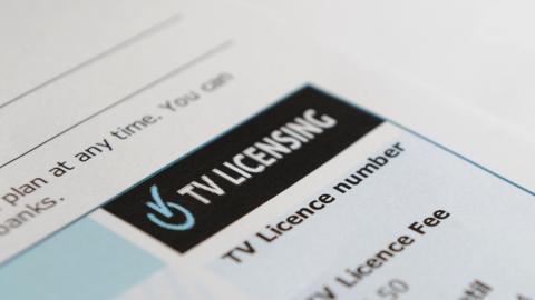 The top righthand corner of a TV licence. which has the TV Licensing logo of a tick within a TV power button in light blue on a black background and the words TV Licensing in bold white font.