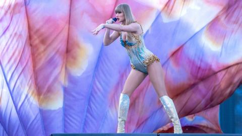 Taylor Swift performing on stage, wearing a blue, silver and gold costume