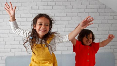 Two children raising their arms