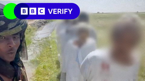 Fighter watches as a line of captured men walk past in al-Seriha